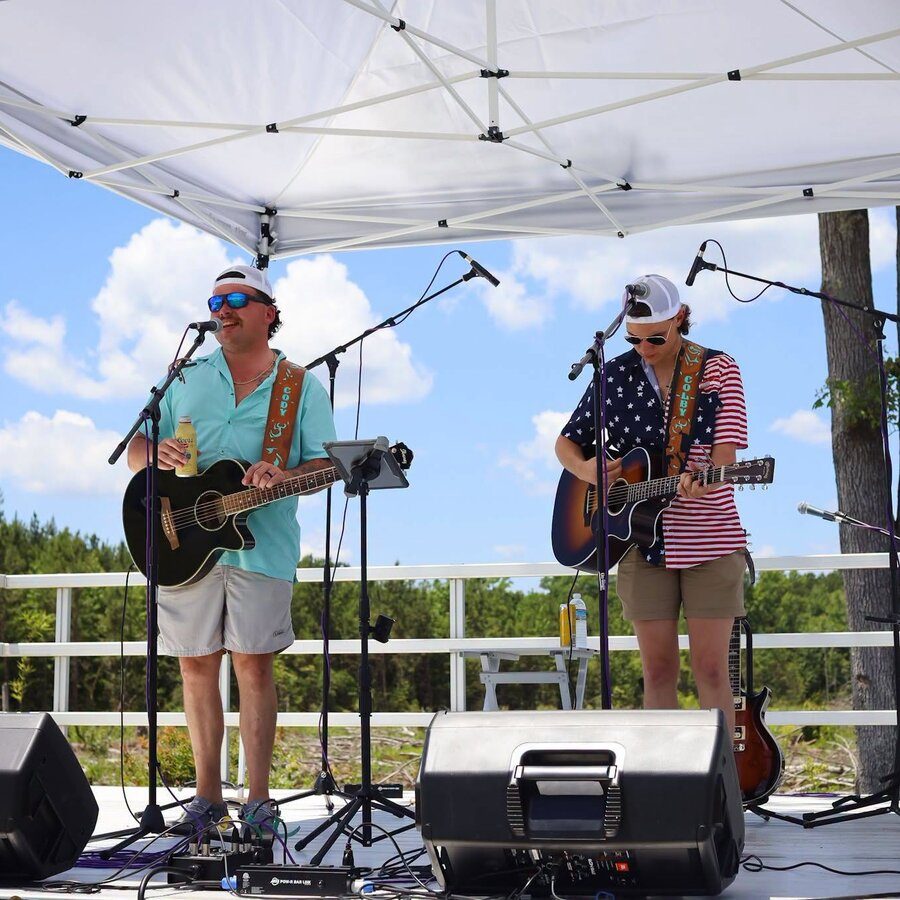 Live band playing for a crowd on the back lawn at Blue 42's Brewing Barn